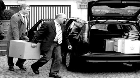 Steuerfahnder tragen sichergestellte Beweismittel in ein Dienstfahrzeiug